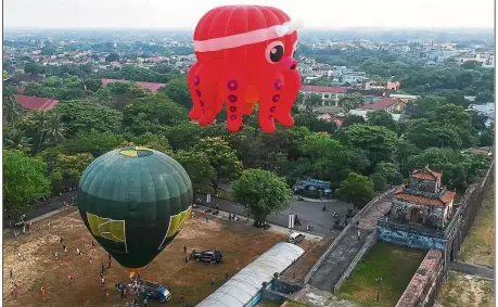  ??  ?? Flights of fancy: An octopus-shaped balloon gets a head start as it rises above the stone citadel of the former capital Hue in central Vietnam. — AFP