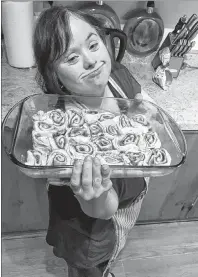  ?? SUBMITTED PHOTO/L’ARCHE CAPE BRETON ?? L’Arche member, Hollywood Mary Oommen, holds up a tray of cinnamon rolls ready to go into the oven during a shift at L’Arche Cape Breton’s Sunflour Bakery and Old Hen Café.