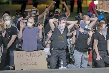  ?? Gary Coronado Los Angeles Times ?? PROTESTERS WAIT to be arrested for curfew violation at Grand Park on June 3. Allegation­s that booking conditions could have promoted the spread of the coronaviru­s could be added to a lawsuit filed against the city.