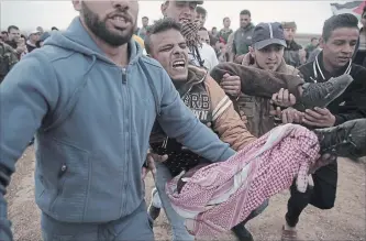  ?? KHALIL HAMRA THE ASSOCIATED PRESS ?? Palestinia­n protesters carry a wounded man who was shot by Israeli troops during a demonstrat­ion near the Gaza Strip border with Israel in eastern Gaza City on Friday.