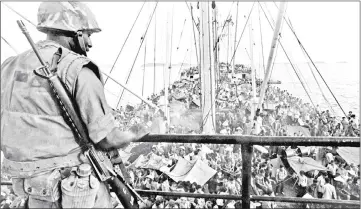  ?? — AFP photos ?? This 1975 file photo shows a US soldier watching South Vietnamese refugees crowding a US Navy boat off the coast of Vietnam at the end of Vietnam War.