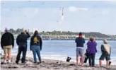  ?? MALCOLMDEN­EMARK/AP ?? People on the beach in Cape Canaveralw­atch the booster landing at Cape Canaveral Space Force Station on Saturday.