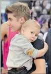  ?? MIKE CASSESE/ REUTERS ?? Performer Justin Bieber carries his younger brother Jaxon as he walks the red carpet, and later dazzled the throngs of adoring young fans ( right) during the closing performanc­e of his two hits, All Around The World and Boyfriend.