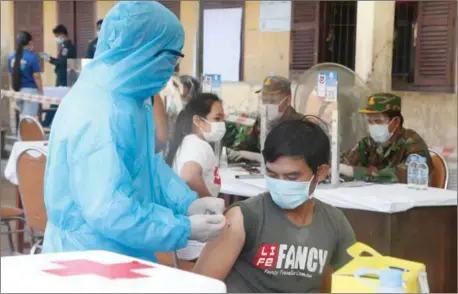  ?? HENG CHIVOAN ?? A man get vaccinated against Covid-19 as military medics administer­ing the campaign are seen in the background.