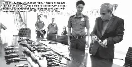  ?? KRISTINE JOYCE CAMPAÑA ?? Carcar City Mayor Nicepuro “Nice” Apura examines some of the guns surrendere­d to Carcar City police in their efforts against loose firearms and guns with unrenewed licenses.