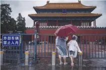  ?? REUTERS ?? PEOPLE stand at the closed gates of the Forbidden City in Beijing, China, July 30, 2023.