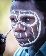  ??  ?? As a prelude to a dance performanc­e, Tiwi islander Freddie Puruntatam­eri dons his clan ‘insignia’.