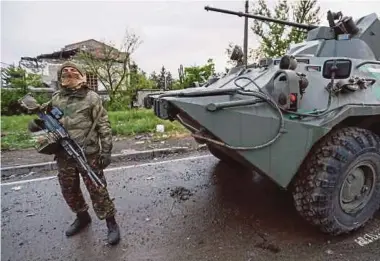  ?? REUTERS PIC ?? A service member of pro-Russian troops standing guard before the departure of Ukrainian soldiers who surrendere­d at the besieged Azovstal steel mill in Mariupol, Ukraine, on Thursday.