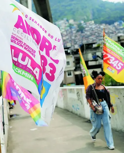  ?? AP ?? Una joven pasea por la favela Rocinha de Rio de Janeiro junto a una bandera a favor de Lula