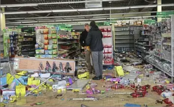  ?? Scott Olson/Getty Images ?? Workers survey damage to a Dollar Tree on Tuesday in a strip mall near the Brooklyn Center police station after it was vandalized and looted during the previous night's unrest in Brooklyn Center, Minn.