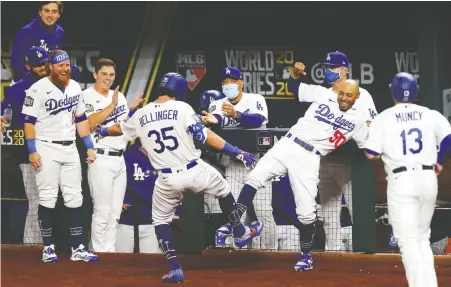  ?? RONALD MARTINEZ/GETTY IMAGES ?? Cody Bellinger of the Los Angeles Dodgers celebrates by tapping toes with Mookie Betts after hitting a two-run homer in the fourth inning of Game 1 as the World Series began at Globe Life Field in Arlington, Texas on Tuesday. The Dodgers downed the Rays 8-3.