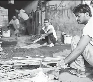  ??  ?? Migrant workers in Kuwait working in the field of blacksmith­ing. (Photo by Tawhid ar-Rahman Flickr)