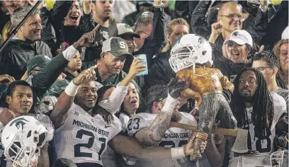  ?? | AP ?? Spartans receiver Cam Chambers ( 21) and linebacker Chris Frey ( 23) hold the Paul Bunyan Trophy after beating Michigan.