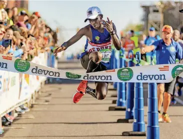  ?? [PHOTO BY CHRIS LANDSBERGE­R, THE OKLAHOMAN] ?? Nathan Chamer jumps across the finish line Sunday as he wins the Oklahoma City Marathon’s men’s race. It was Chamer’s first marathon.