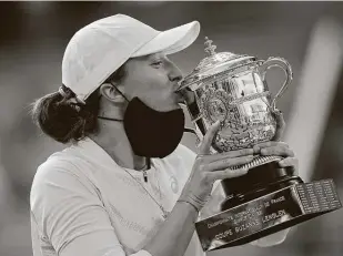  ?? Christophe Ena / Associated Press ?? Poland’s Iga Swiatek, 19, kisses the trophy after winning the final match of the French Open against American Sofia Kenin with a dominant 6-4, 6-1 victory on Saturday.