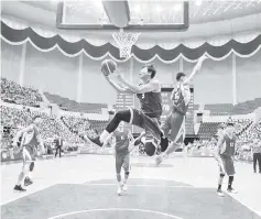  ?? - AFP photo ?? This photo taken on July 5, 2018 shows players from North (red) and South Korea (blue) competing during a friendly men’s basketball match at the Ryugyong Chung Ju-Yung Indoor Stadium in Pyongyang.The North Korean men’s team won 82-70.A group of 50 male...