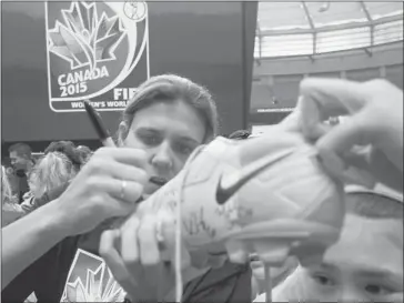  ?? Jonathan Hayward/the Canadian Press ?? Team Canada’s Christine Sinclair signs autographs for young soccer fans as FIFA unveils the official emblem for the 2015 Women’s World Cup during a ceremony in Vancouver on Friday. The newly expanded World Cup will be contested coast-to-coast at venues...