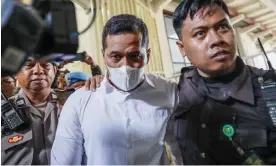  ?? ?? Police officer Bambang Sidik Achmadi, centre, is escorted to court in Surabaya, Indonesia, before being acquitted of negligence, along with another office, over a crowd crush in Kanjuruhan stadium that killed 135 people in October 2022. Photograph: Made Nagi/EPA