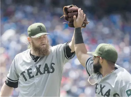  ?? CHRIS YOUNG/THE CANADIAN PRESS ?? Texas Rangers pitcher Andrew Cashner high-fives second baseman Rougned Odor during Sunday’s MLB game at Rogers Centre. Cashner piched five-hit ball over seven innings as the Rangers salvaged the third game of the series with a 3-1 win Sunday.