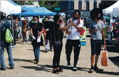  ?? JANE TYSKA — STAFF PHOTOGRAPH­ER ?? People wander through the Akoma Outdoor Market at the new East Oakland Black Cultural Zone on Sept. 20. The Zone is in a trianglesh­aped lot along 73rd Avenue and Foothill Boulevard. The 54,000-acre site, also known as Liberation Park, has been vacant since 2007.