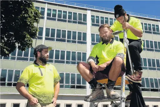  ?? PHOTOS: STEPHEN JAQUIERY ?? Sheared experience . . . Hayward College contractor­s Todd Hendry (left) and Nathan Hastie get a cut from the Gibfixing barber Joel Taniora, on a work break yesterday. Hayward College contractor Todd Hendry poses halfway through a beard trim.