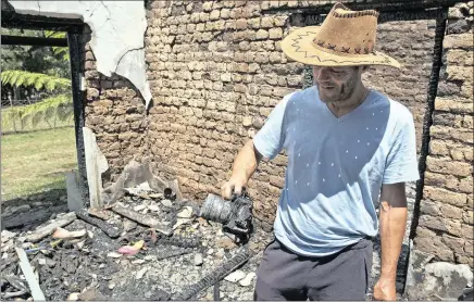  ?? PICTURES: EPA ?? Firefighti­ng helicopter pilot Mike Bothma looks at the remains of a camera passed down through generation­s in his family at his burnt home in Greyton on Wednesday. In the bottom picture, Bothma flies his helicopter while battling a blaze on the...