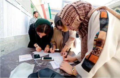  ?? AFP ?? FILLING FORMS: Women prepare to cast their ballot at a polling station in southern Tehran on Friday. —