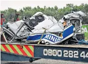  ??  ?? Part of the remains of the minibus, left, which was cut in two in the crash, are removed from the scene on the M1. Right, the FedEx truck involved in the accident