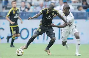  ??  ?? Columbus Crew’s Kekuta Manneh, left, is pressured by Vancouver Whitecaps’ Aly Ghazal while trying to move the ball upfield.