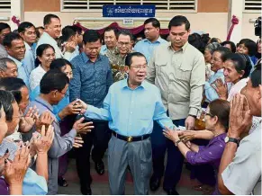  ??  ?? No middle ground: Hun Sen (centre) greeting commune councillor­s at a polling station in Kandal province. — AFP