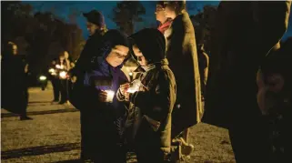  ?? THE NEW YORK TIMES ?? Residents gather together at City Park on Nov. 28 for a vigil for the victims of the Walmart shooting in Chesapeake.