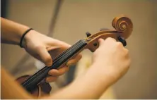  ??  ?? Gardner tunes a violin for a Bahia student. She also heads the education equity committee for the county Youth Commission.