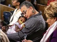  ?? PHOTOS BY AMANDA ANDRADE-RHOADES/ASSOCIATED PRESS ?? Left: Marie Johns holds her 1-year-old daughter during Palm Sunday services at the Metropolit­an AME Church. Black Protestant­s’ monthly church attendance declined 15% from 2019 to 2023, according to a Pew Research study.