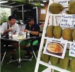  ??  ?? Pelancong asing sedang menikmati durian bermutu tinggi dalam persekitar­an selesa.