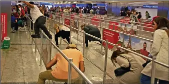  ??  ?? Carnage: Terrified passengers duck under barriers as they rush to leave the terminal