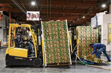  ?? Jessica Christian/The Chronicle ?? Workers move vegetable pallets through the warehouse at the Alameda County Food Bank, which has had to shift the food items it buys, focusing on lower-cost items that can be purchased in higher quantities.