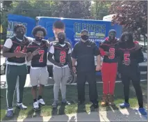  ??  ?? This is a different kind of football huddle. Michigan Collegiate coach John Guth is flanked by his senior captains prior to a food distributi­on effort. The food was provided by Gleaners.