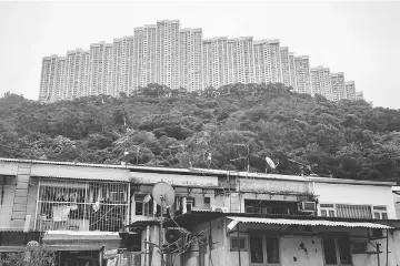  ??  ?? Above left, picture taken on May 25 shows people walking past a building in the Wonderland Villas hilltop residentia­l complex in the Kwai Fong district of Hong Kong. Red-whiskered bulbuls start chirping around 5.00am at Wonderland Villas, a hilltop...