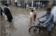  ?? (AP/Muhammad Sajjad) ?? Youngsters wade through a flooded street caused by heavy rain in Peshawar, Pakistan, on Monday.