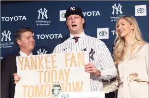  ?? Mark Lennihan / Associated Press file photo ?? New York Yankees pitcher Gerrit Cole, center, holds a sign he used as a young Yankees fan, as he is introduced as the baseball club’s newest player on Dec. 18, 2019, in New York. He is joined by team owner Hal Steinbrenn­er, left, and his wife, Amy Crawford. The Coles purchased a home in Greenwich.
