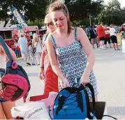  ?? George Wong / For the Chronicle ?? Admission to the Aug. 13 Katy Summer Tailgate is a backpack or a bag full of school supplies. Last year, Amiee Dobson, above, dropped off a backpack.