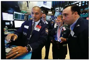  ?? AP/RICHARD DREW ?? Specialist Mark Otto (left) works with traders Friday at his post on the floor of the New York Stock Exchange as benchmark stocks ended a turbulent week on a positive note.