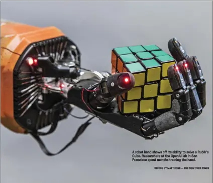  ?? PHOTOS BY MATT EDGE — THE NEW YORK TIMES ?? A robot hand shows off its ability to solve a Rubik’s Cube. Researcher­s at the OpenAI lab in San Francisco spent months training the hand.