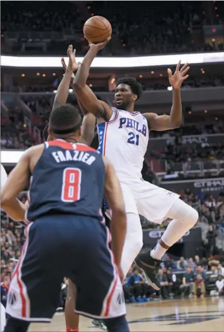  ?? NICK WASS — THE ASSOCIATED PRESS ?? Sixers center Joel Embiid (21) shoots as Wizards guard Tim Frazier (8) watches during the first half Sunday in Washington.