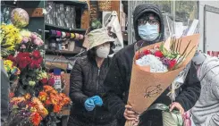  ?? STEPHANIE KEITH GETTY IMAGES ?? A doctor buys Mother’s Day bouquets on Friday in New York. Being isolated from family will hurt especially tomorrow for the many whose mothers are in long-term-care homes.