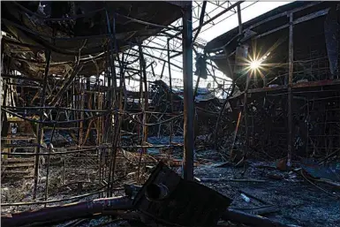  ?? BERNAT ARMANGUE / AP ?? The sun’s rays pass through charred structures of one of the shelled sections of the Barabashov­o market in Kharkiv, eastern Ukraine on Monday.