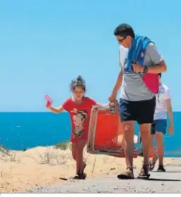  ??  ?? Un padre y sus hijos caminan por un sendero en la playa este fin de semana.