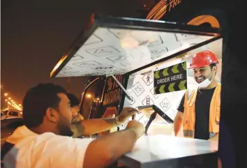  ?? AFP ?? Bader Al Ajmi serves customers from his food truck at a main street in Riyadh. More young Saudis are starting businesses and taking up blue-collar jobs in a new wave of austerity.