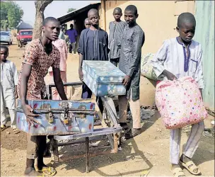  ??  ?? ORDEAL SURVIVORS: Three boys carry their school belongings back home to Ketare, Nigeria, on Saturday, two days after being released by Boko Haram terrorists.