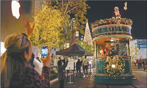  ?? (AP/Ashley Landis) ?? Santa Claus waves to shoppers from a safe distance at the top level of a trolly at The Grove shopping center in Los Angeles. Santa visits were canceled due to the spread of covid-19.